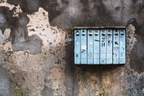 Weathered mailbox hanging on crumbling concrete wall on city street — Stock Photo
