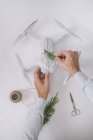 Male hands wrapping drone as Christmas gift with fir branch and twine on white background — Stock Photo