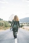 Visão traseira da mulher vestindo traje de astronauta andando ao longo da estrada rural — Fotografia de Stock