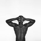 Visão traseira do homem Africano Americano muscular sem camisa em ganga em pé contra a parede branca — Fotografia de Stock