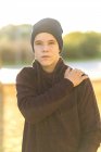Portrait of a teenage boy in hat and hoodie standing outdoors — Stock Photo