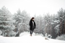 Bella giovane donna in abito elegante guardando lontano mentre in piedi vicino all'albero coperto di neve nella giornata fredda in campagna meravigliosa — Foto stock
