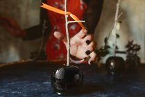 Mão feminina tomando maçã caramelizada preta para o dia das bruxas — Fotografia de Stock