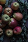 Frische reife Äpfel und Blätter auf rustikalem Tisch — Stockfoto