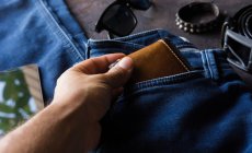 Vista aérea de ropa de mezclilla para hombre con billetera, brazalete de tachuelas, teléfono inteligente. y zapatos de cuero negro - foto de stock
