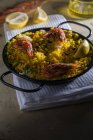 Традиционная испанская паэлья маринера с рисом, креветками, кальмарами и мидиями в кастрюле на салфетке — стоковое фото