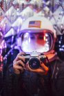 Girl wearing old space helmet and costume holding photo camera — Stock Photo