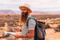 Homme tenant carte et boussole rétro debout sur fond flou de désert majestueux — Photo de stock