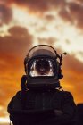 Girl wearing old space helmet and spacesuit against dramatic sky at sunset — Stock Photo