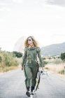 Женщина-астронавт с вьющимися волосами, идущая по дороге на природе — стоковое фото