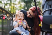Madre che gioca con la bambina nel parco soleggiato — Foto stock