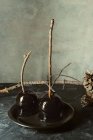 Чорні карамельні яблука з паличками для Хеллоуїна на чорній тарілці — стокове фото