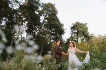 Luva que segura a mão da noiva em uma floresta — Fotografia de Stock