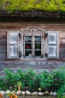 Ornate window on wall of wooden countryside house with mossy roof — Stock Photo