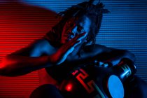 Jovem homem rastafarian africano gosta de ensaiar e joga udu, iluminação colorida vermelho e azul — Fotografia de Stock