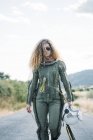 Женщина-астронавт с вьющимися волосами, идущая по дороге на природе — стоковое фото