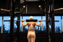 Молода блондинка робить вправи з барбелом в спортзалі — стокове фото