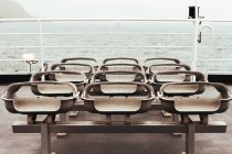Fila di sedili ripiegati sul ponte vuoto della moderna nave che naviga in mare — Foto stock