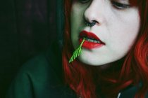 Крупным планом рыжеволосая молодая женщина с пирсингом и иглой во рту — стоковое фото