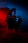 Young african rastafarian man enjoys rehearsing and plays udu, colored lighting red and blue — Stock Photo