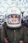 Smiling girl wearing old space helmet and spacesuit on foil background — Stock Photo