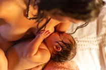 Crop donna allattamento al seno bambino sul letto — Foto stock