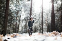 Pretty young female in stylish outfit looking away while standing near tree covered with snow on cold day in wonderful countryside — Stock Photo
