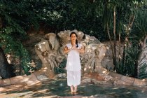 Жінка з закритими очима стоїть у фонтанній воді під час виконання йоги в парку — стокове фото