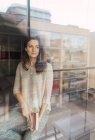 Donna adulta con libro in piedi vicino al divano e alla finestra — Foto stock