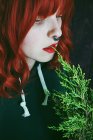 Primo piano della giovane donna dai capelli rossi che morde il ramoscello di abete — Foto stock