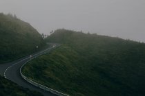 Порожня автомагістраль, закладена на зеленому пагорбі на тлі сірого неба — стокове фото