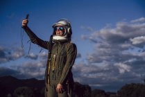 Astronauta sonriente tomando selfie teléfono móvil en la naturaleza de la noche - foto de stock