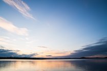 Surface d'un lac bleu tranquille avec un ciel spectaculaire au coucher du soleil — Photo de stock