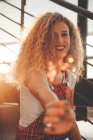Smiling young curly woman showing blurred sparkler on stairs in sunshine — Stock Photo