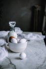 Bol d'œufs de poulet et bouteille de produits laitiers frais debout sur une table en marbre dans la cuisine — Photo de stock