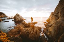 Unrecognizable person standing on cliff near sea — Stock Photo