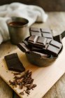 Pedaços de chocolate escuro em tábua de corte de madeira — Fotografia de Stock