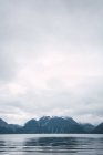 Eaux tranquilles du lac et montagnes rocheuses sous un ciel nuageux, Laponie — Photo de stock