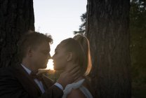 Groom et mariée nez à nez avant de s'embrasser au coucher du soleil — Photo de stock