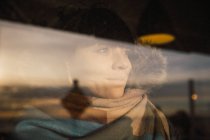 Femme regardant par la fenêtre — Photo de stock