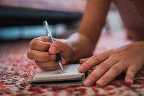 Nahaufnahme weiblicher Hände, die in ein Notizbuch auf dem Boden schreiben — Stockfoto