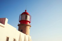 Red lighthouse and white building — Stock Photo