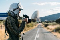 Beautiful woman using old camera dressed as an astronaut. — Stock Photo