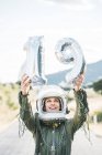 Happy woman in helmet and spacesuit posing with number 19 against sky — Stock Photo