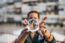 Жінка тримає кришталевий м'яч з відображенням у місті — стокове фото