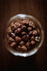 Top view of glass jar full of brown hazelnuts on wooden table — Stock Photo