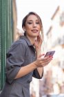 Mulher usando smartphone perto de edifício na rua — Fotografia de Stock
