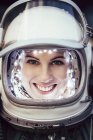 Улыбающаяся девушка в старом космическом шлеме и скафандре на фоне фольги — стоковое фото