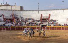 España, Tomelloso - 28. 08. 2018. Vista de toreros montando caballos en una plaza de toros de arena con gente en la tribuna - foto de stock