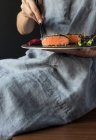 Donna che parla deliziosi filetti di salmone con bacchette — Foto stock